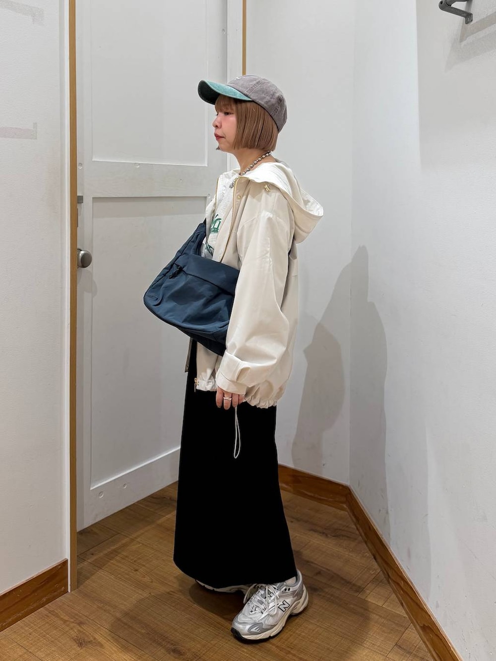 グレー系のスウェット、ベージュ系のマウンテンパーカー、グリーン系のショルダーバッグを着用したレディースの冬コーディネートの3枚目の写真