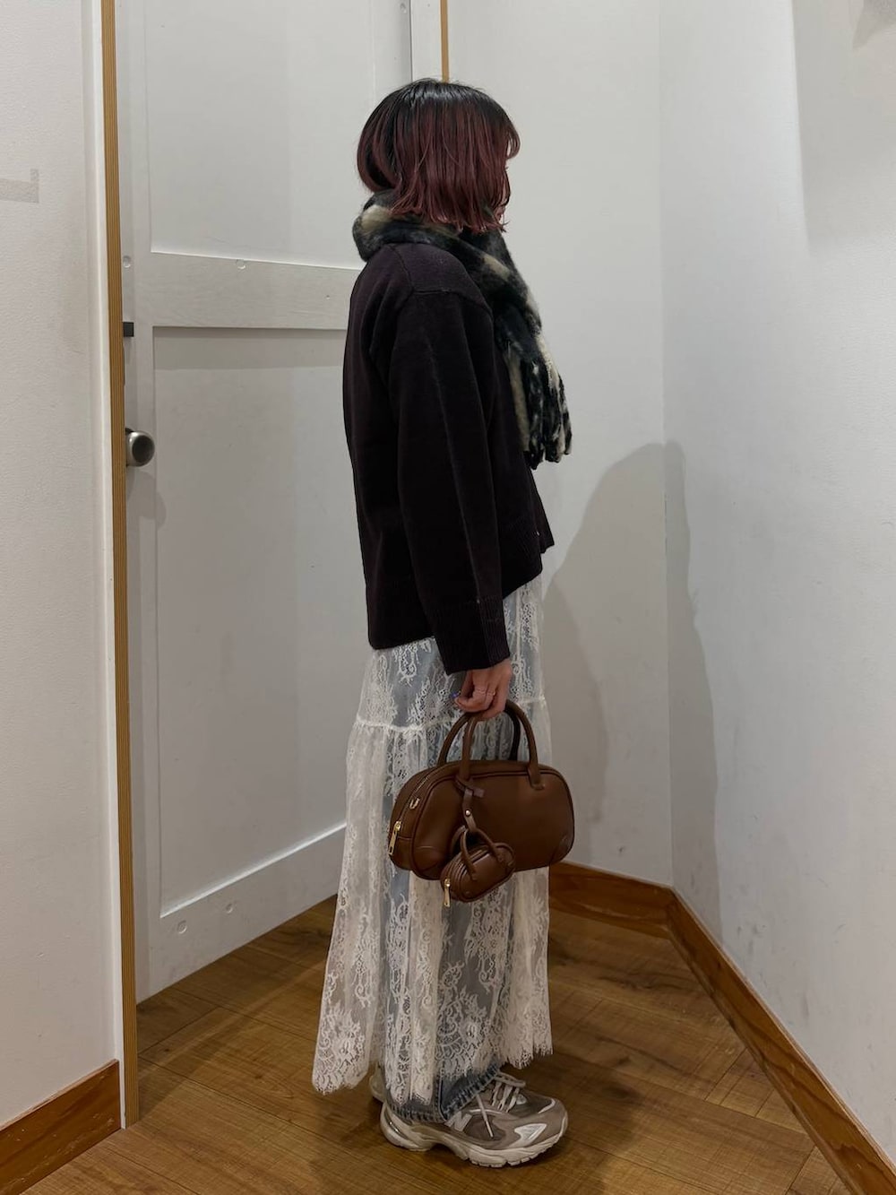 ブルー系のデニムパンツ、ブラウン系のワンピース、ブラウン系のハンドバッグを着用したレディースの秋コーディネートの3枚目の写真