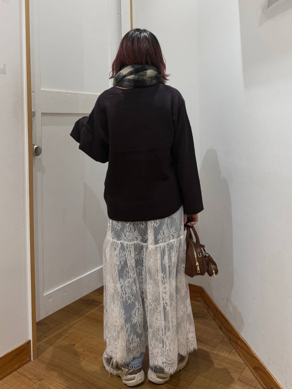 ブルー系のデニムパンツ、ブラウン系のワンピース、ブラウン系のハンドバッグを着用したレディースの秋コーディネートの4枚目の写真