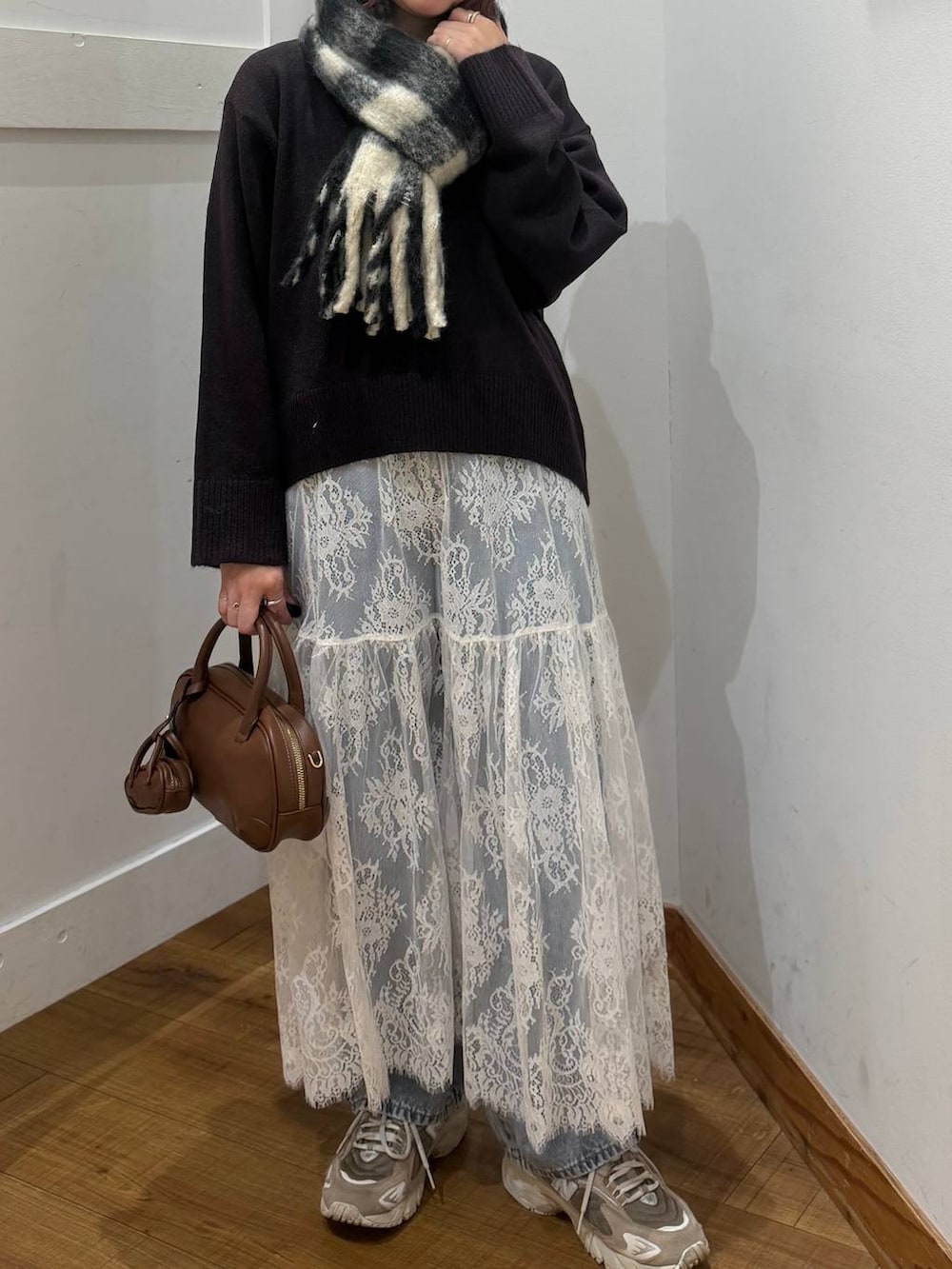 ブルー系のデニムパンツ、ブラウン系のワンピース、ブラウン系のハンドバッグを着用したレディースの秋コーディネートの2枚目の写真