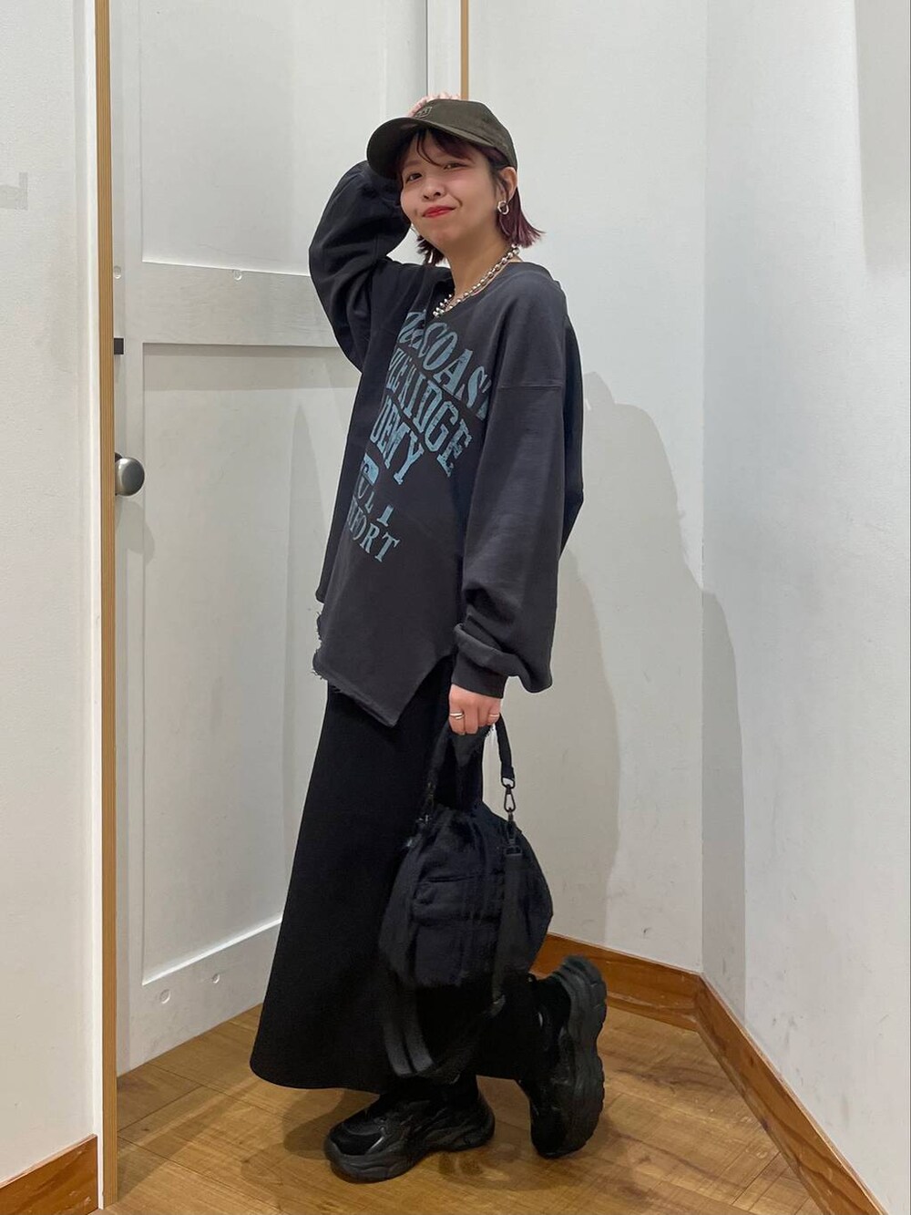 ブラック系のショルダーバッグ、ブラック系のスカート、ブラック系のスニーカーを着用したレディースの秋コーディネートの2枚目の写真