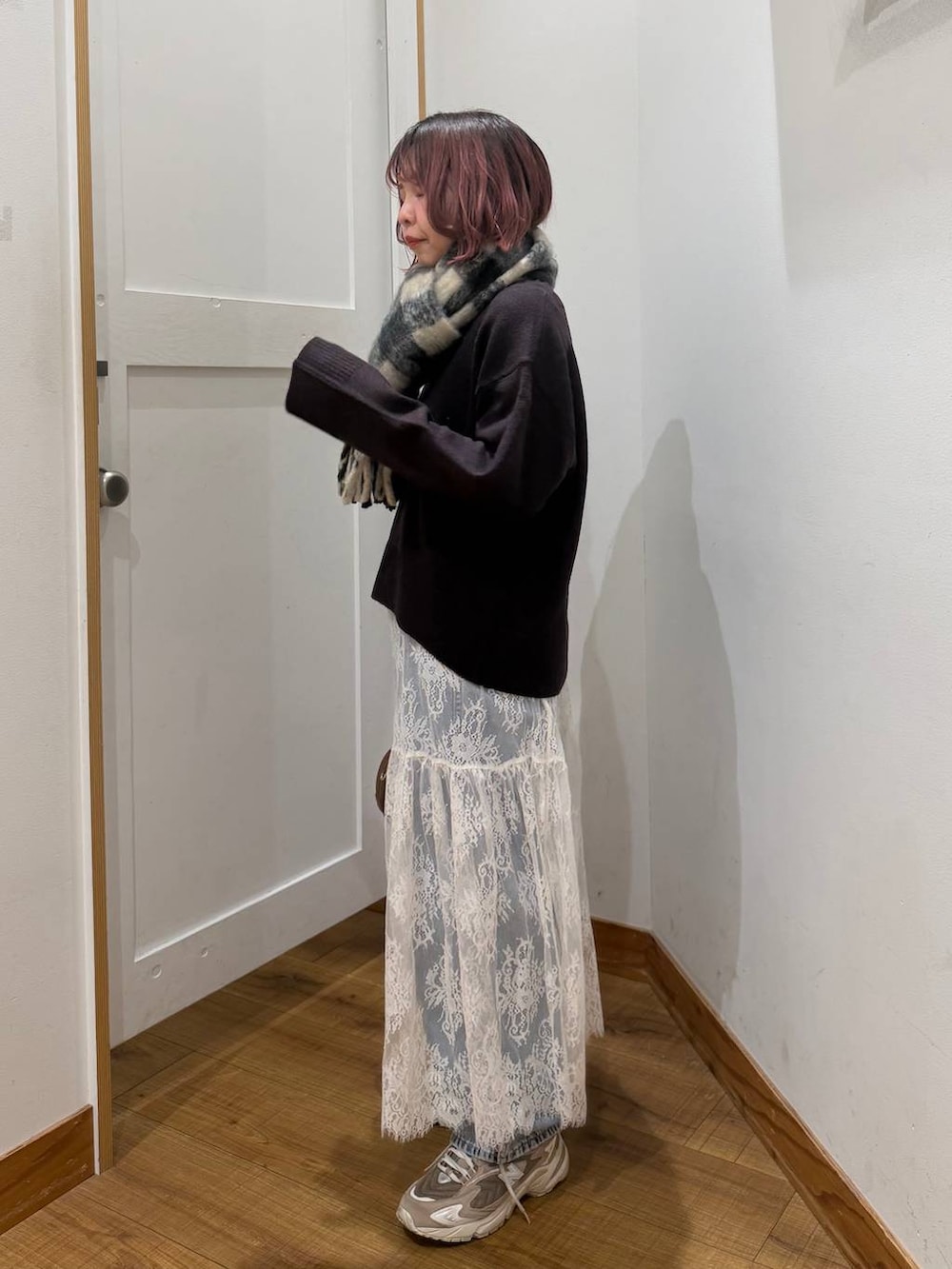 ブルー系のデニムパンツ、ブラウン系のワンピース、ブラウン系のハンドバッグを着用したレディースの秋コーディネートの5枚目の写真