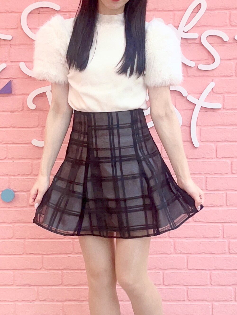 ホワイト系のスニーカー、ブラック系のスカート、ホワイト系のニット/セーターを着用したレディースの冬コーディネートの2枚目の写真