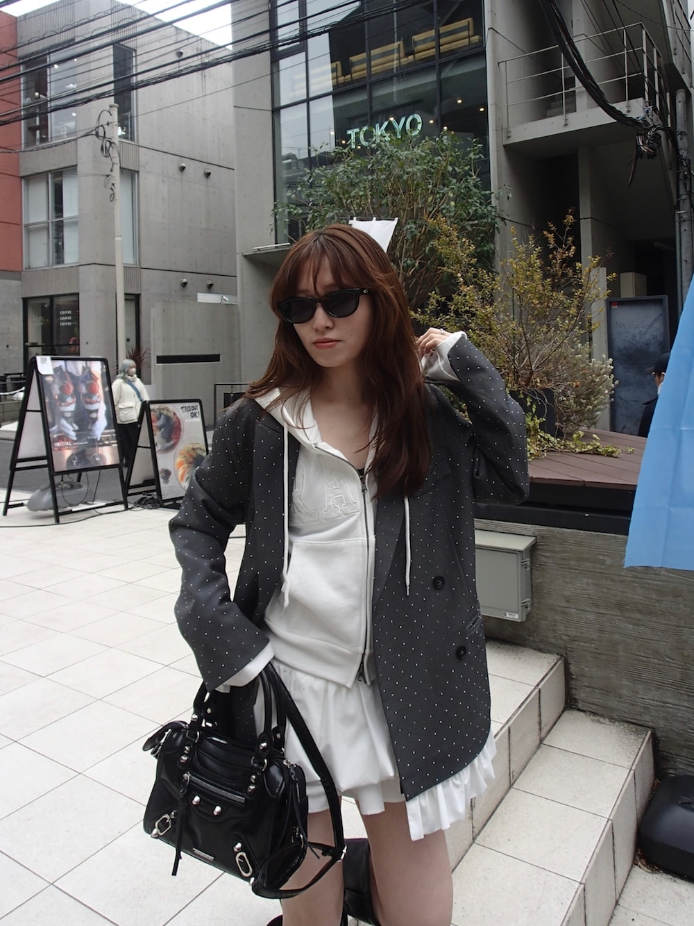 ホワイト系のパーカー、グレー系のテーラードジャケット、ホワイト系のスカートを着用したレディースの春コーディネートの2枚目の写真