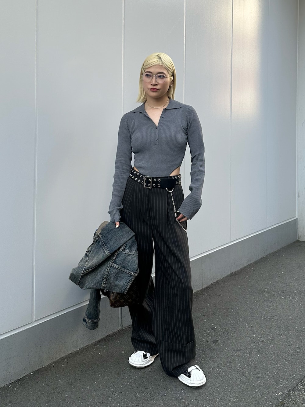 グレー系のポロシャツ、ブルー系のデニムジャケット、ブラック系のスニーカーを着用したレディースの春コーディネートの2枚目の写真