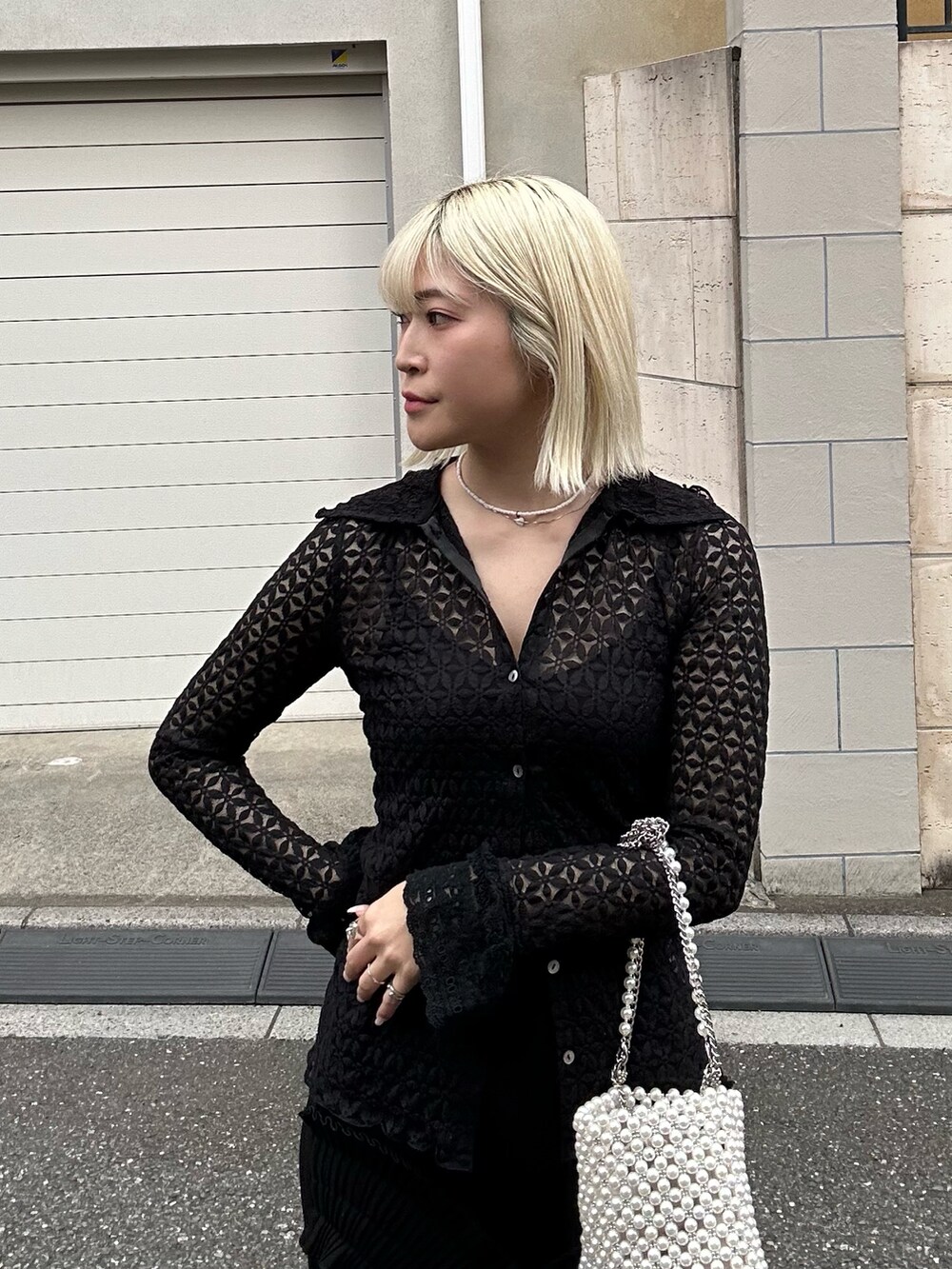 ブラック系のシャツ/ブラウス、ブラック系のスカート、ホワイト系のバッグを着用したレディースの春コーディネートの2枚目の写真