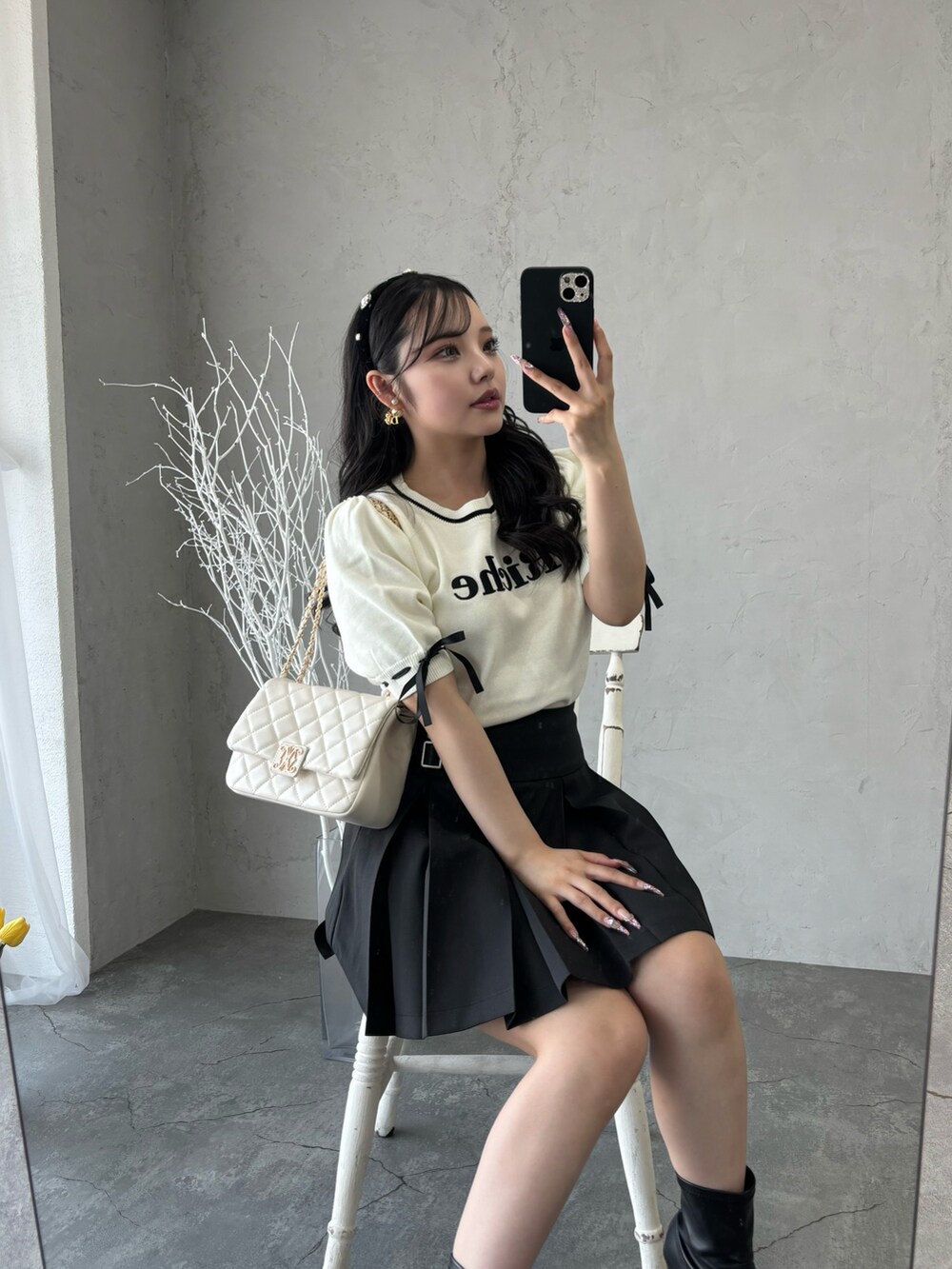 ブラック系のスカート、ホワイト系のニット/セーターを着用したレディースの春コーディネートの2枚目の写真