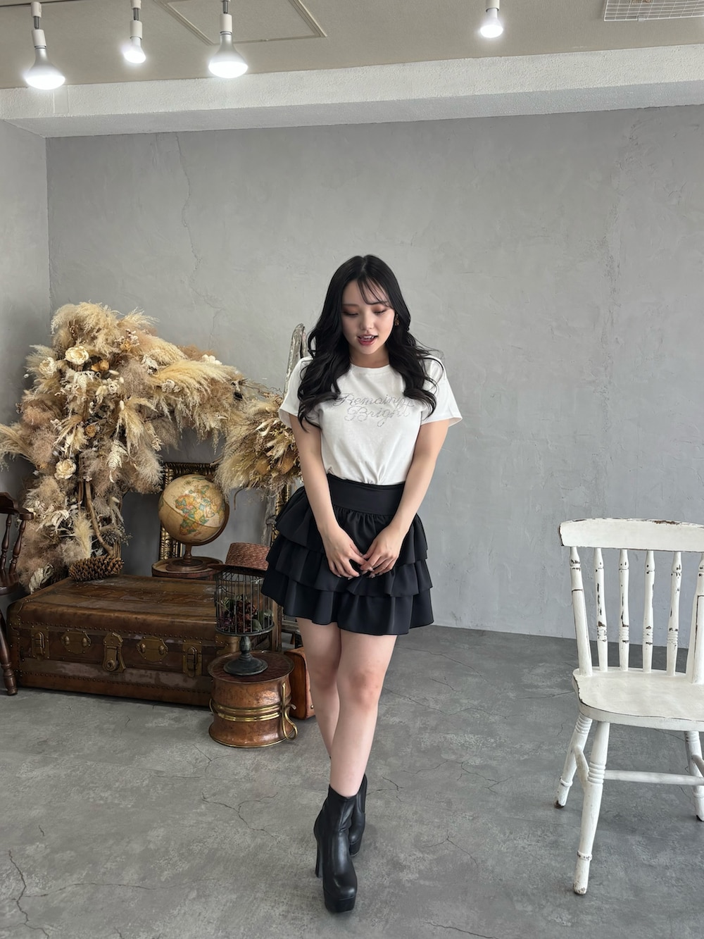 ブラック系のスカート、ホワイト系のTシャツ/カットソーを着用したレディースの夏コーディネートの2枚目の写真