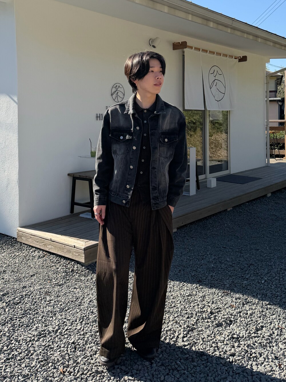 ブラック系のデニムジャケット、ブラウン系のカーディガン/ボレロ、ブラウン系のスラックスを着用したメンズの秋コーディネートの2枚目の写真