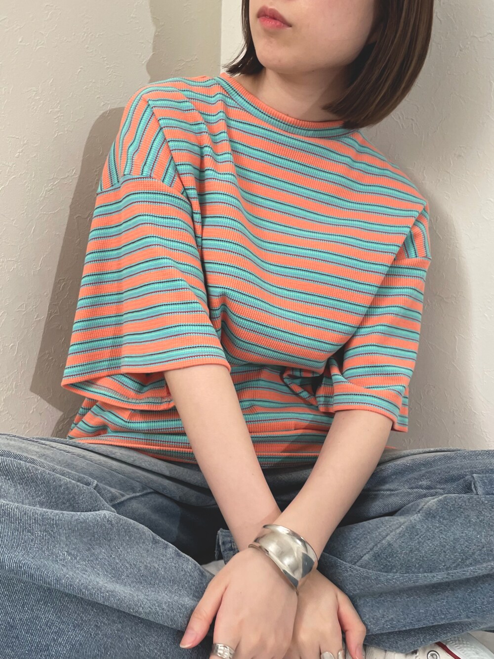 オレンジ系のTシャツ/カットソーを着用したレディースの春コーディネートの3枚目の写真
