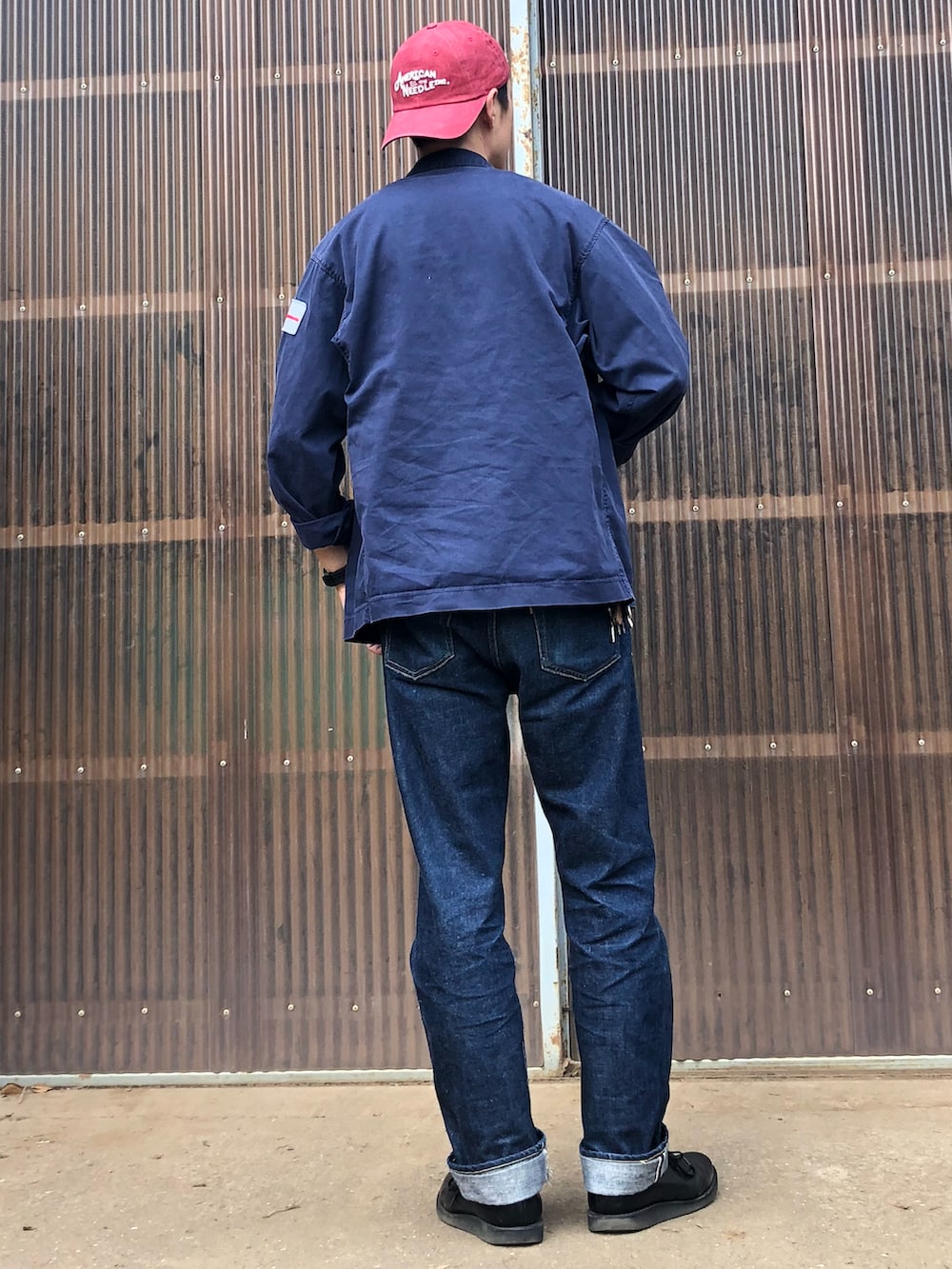 ブルー系のデニムパンツ、ブラック系のブーツ、ブルー系のミリタリージャケットを着用したメンズの秋コーディネートの2枚目の写真