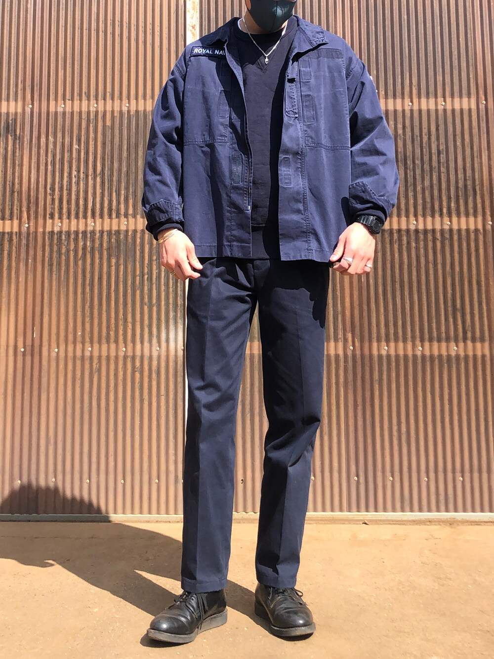 ブルー系のスラックス、ブラック系のブーツ、ブルー系のミリタリージャケットを着用したメンズの春コーディネートの3枚目の写真