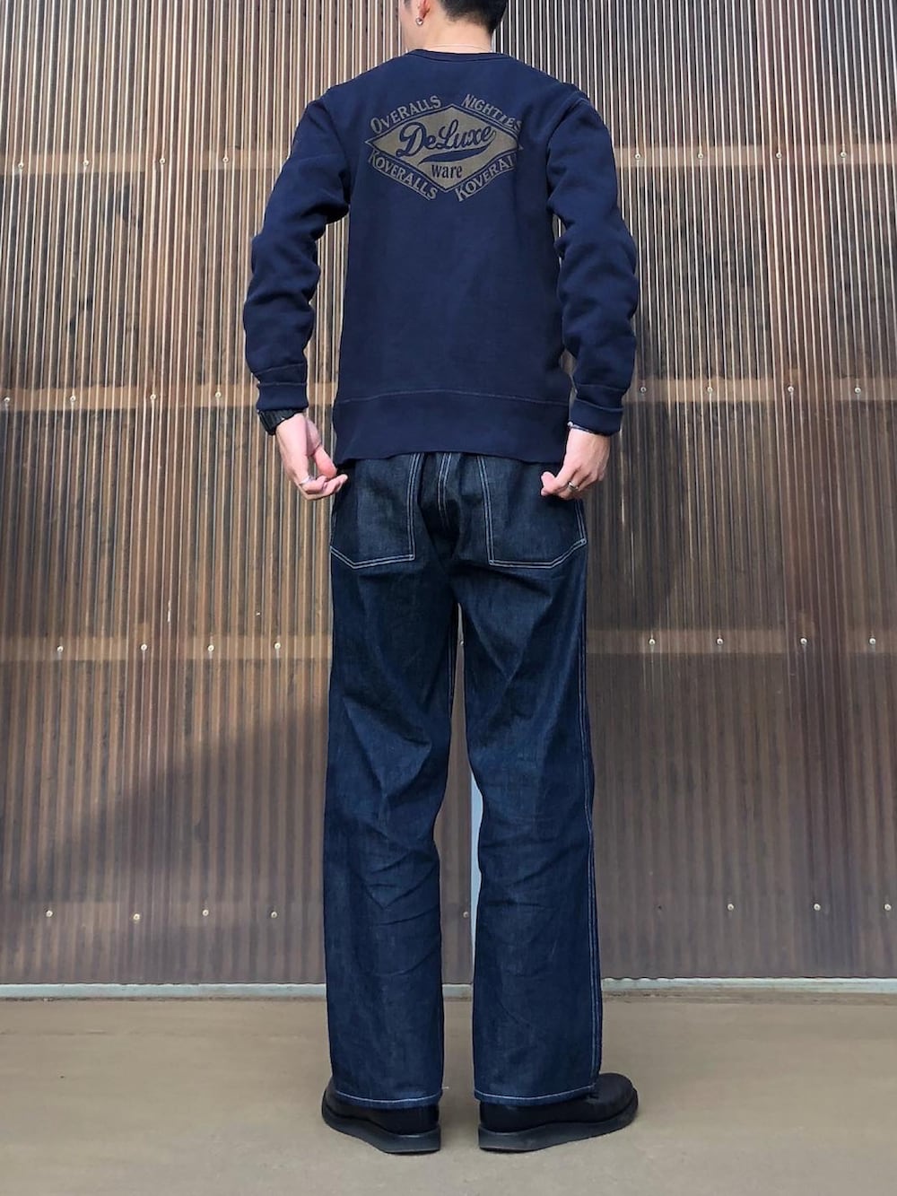 ブルー系のスウェット、ブルー系のデニムパンツ、ブラック系のブーツを着用したメンズの秋コーディネートの2枚目の写真