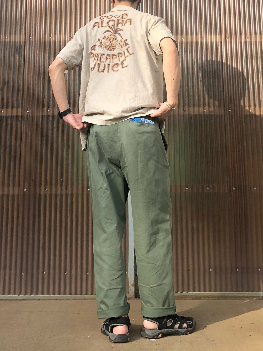 グリーン系のチノパンツ、ブラック系のサンダル、ベージュ系のシャツ/ブラウスを着用したメンズの夏コーディネートの2枚目の写真
