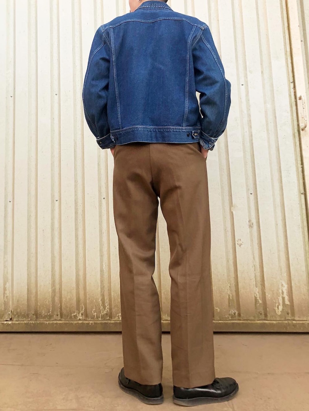 グリーン系のスウェット、ブルー系のデニムジャケット、ブラウン系のスラックスを着用したメンズの秋コーディネートの2枚目の写真