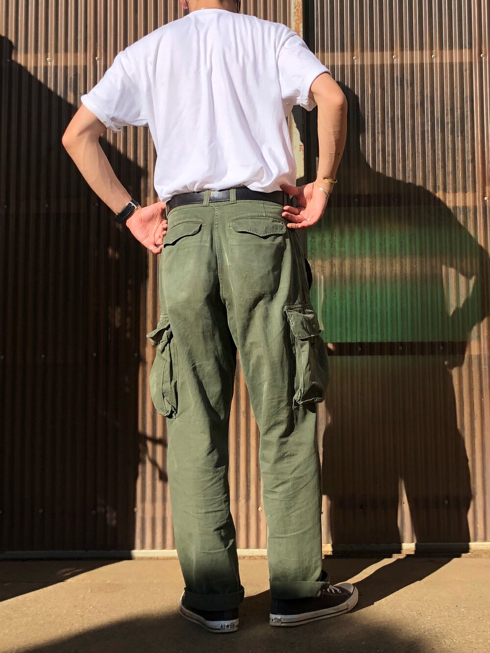 ホワイト系のTシャツ/カットソー、グリーン系のカーゴパンツ、ブラック系のスニーカーを着用したメンズの夏コーディネートの2枚目の写真