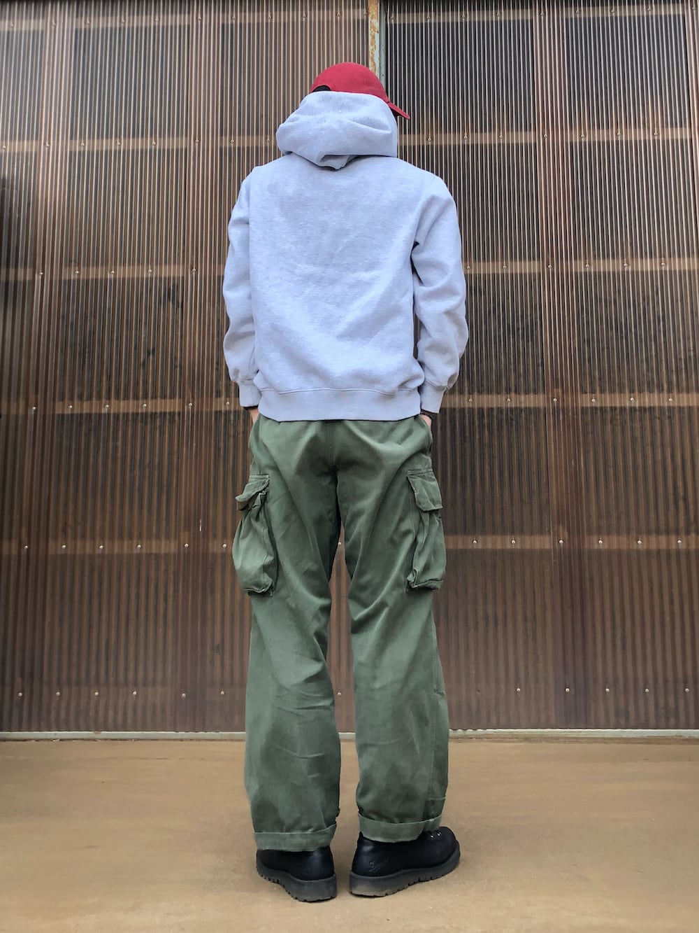 グレー系のパーカー、グリーン系のカーゴパンツ、ブラック系のブーツを着用したメンズの秋コーディネートの2枚目の写真