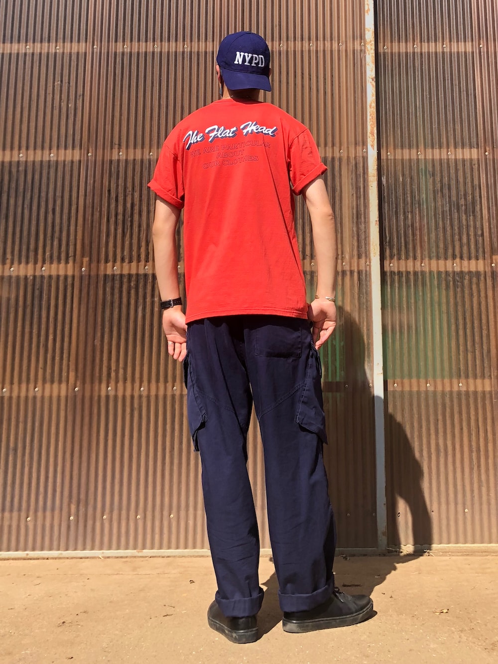 レッド系のTシャツ/カットソー、ブルー系のカーゴパンツ、ブラック系のシューズを着用したメンズの夏コーディネートの2枚目の写真