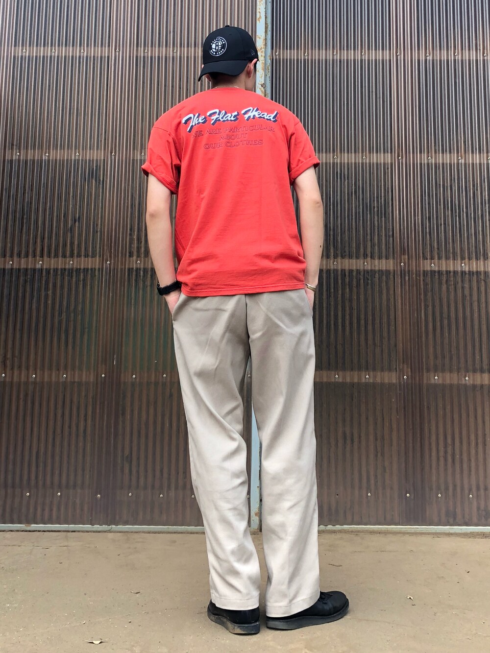 レッド系のTシャツ/カットソー、ベージュ系のチノパンツ、ブラック系のブーツを着用したメンズの夏コーディネートの2枚目の写真