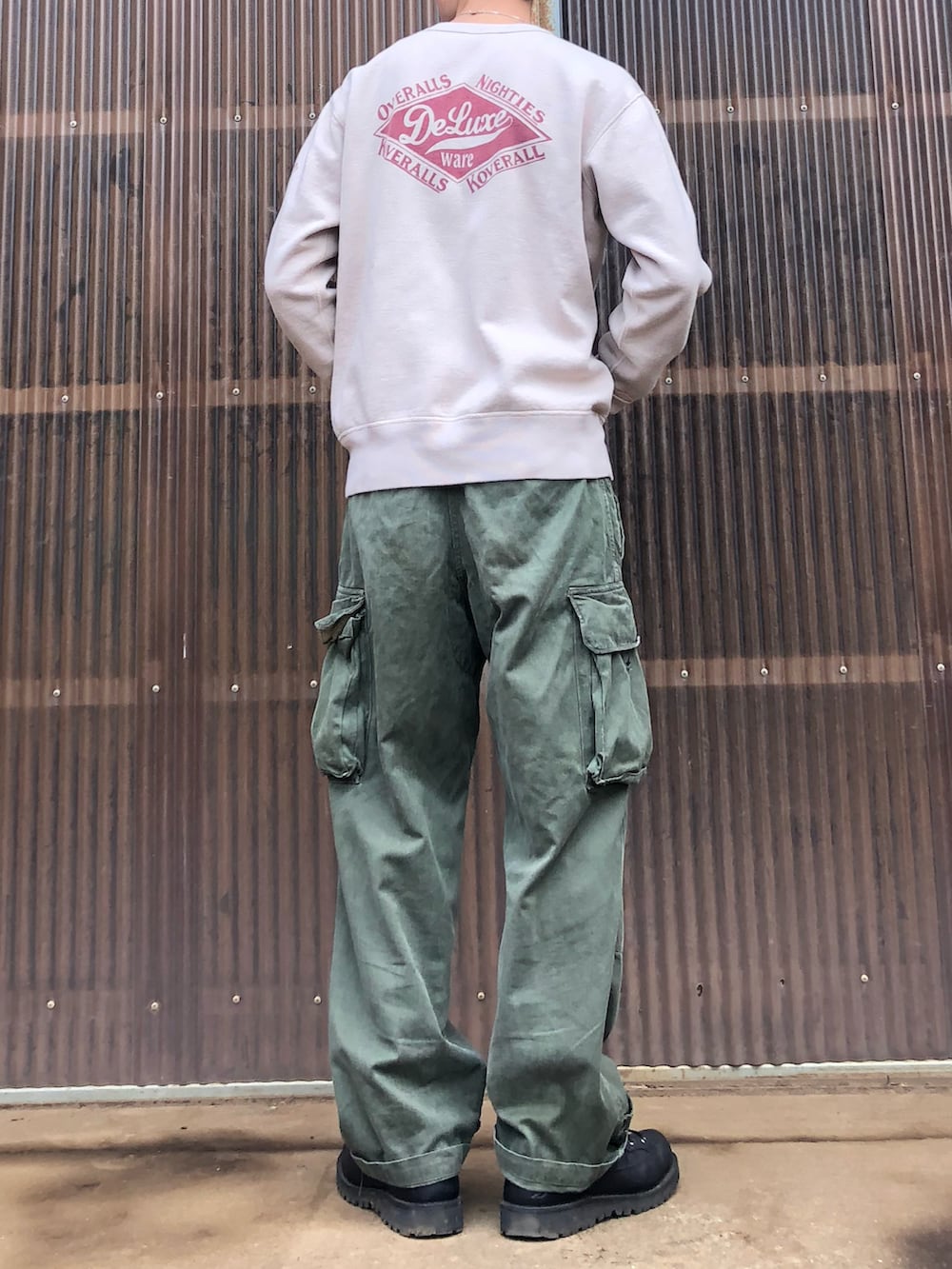 ベージュ系のスウェット、グリーン系のカーゴパンツ、ブラック系のブーツを着用したメンズの秋コーディネートの2枚目の写真