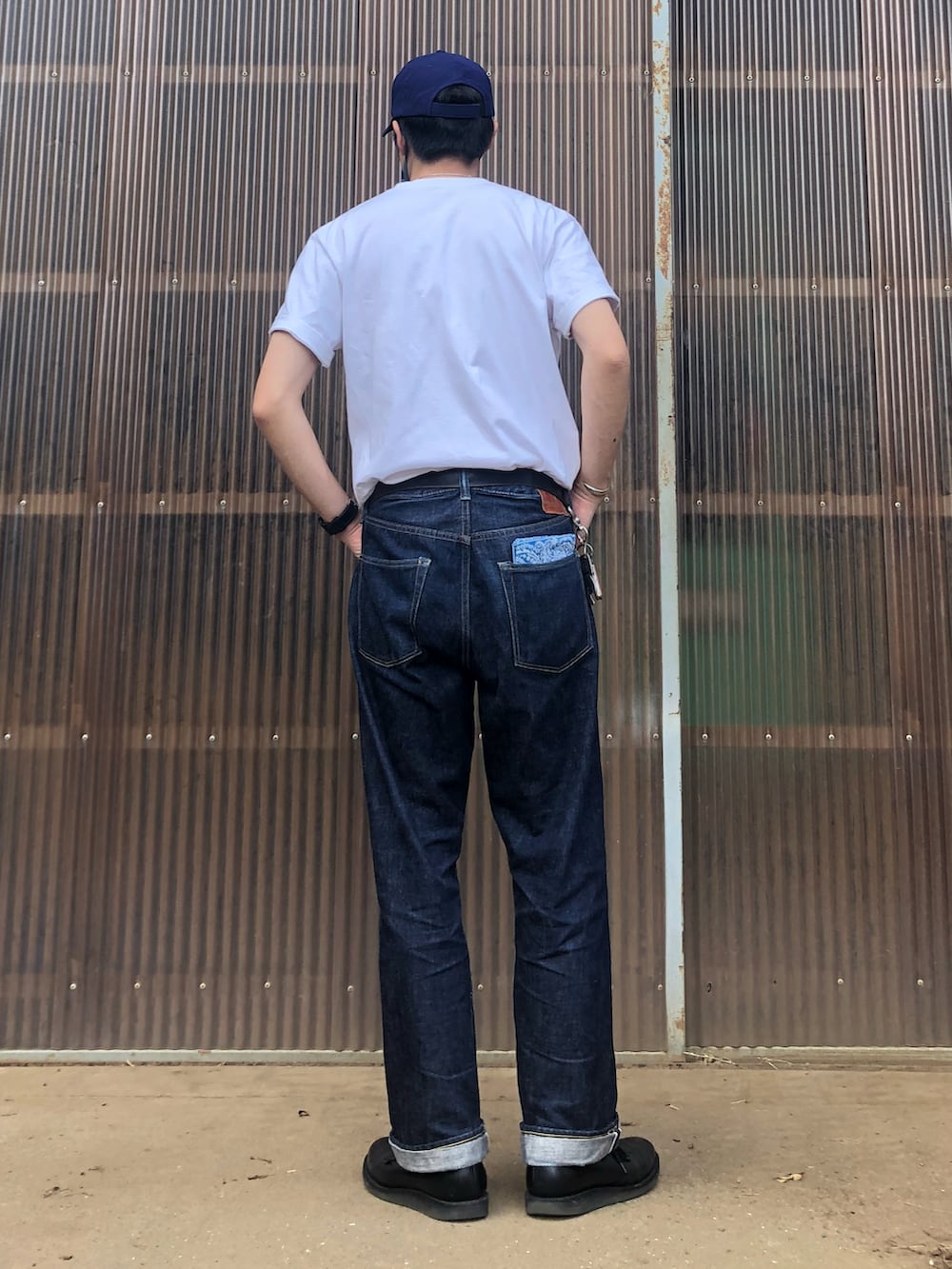 ホワイト系のTシャツ/カットソー、ブルー系のデニムパンツ、ブラック系のブーツを着用したメンズの夏コーディネートの2枚目の写真