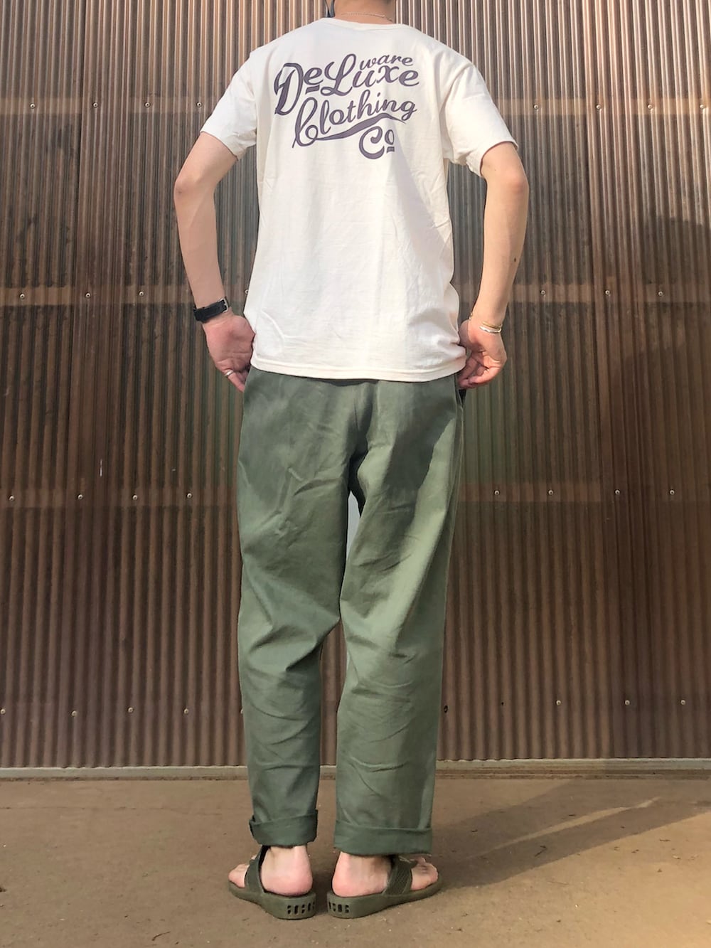 ホワイト系のTシャツ/カットソー、グリーン系のサンダル、グリーン系のチノパンツを着用したメンズの夏コーディネートの2枚目の写真