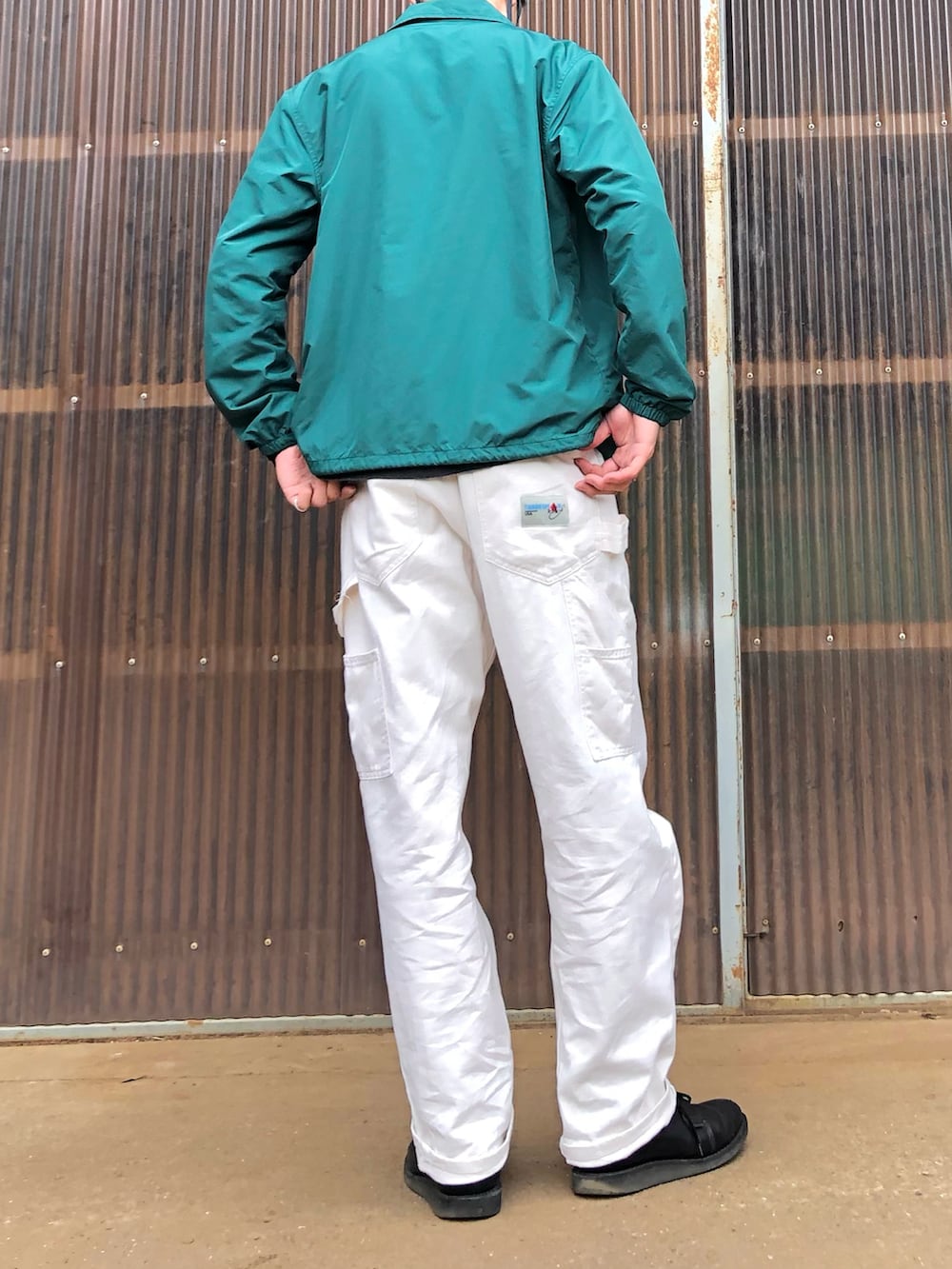 ブラック系のTシャツ/カットソー、グリーン系のナイロンジャケット、ブラック系のブーツを着用したメンズの春コーディネートの2枚目の写真