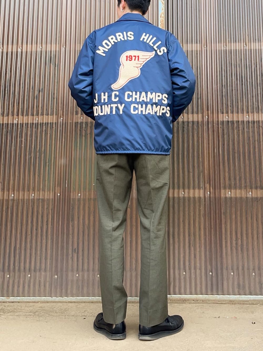 グリーン系のスラックス、ブラック系のブーツ、ブルー系のナイロンジャケットを着用したメンズの冬コーディネートの2枚目の写真