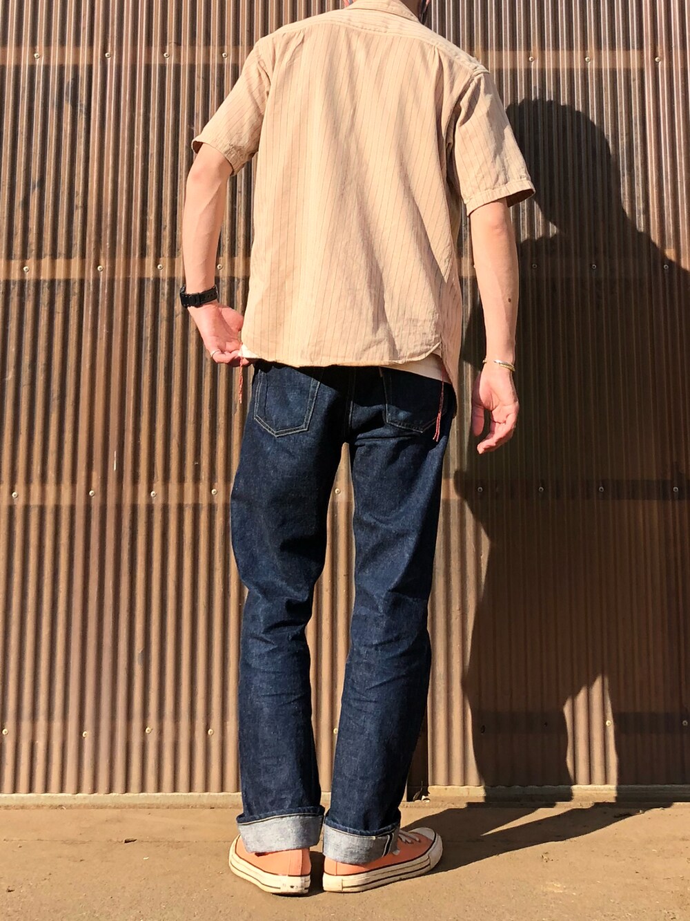 ブルー系のデニムパンツ、ピンク系のスニーカー、ホワイト系のTシャツ/カットソーを着用したメンズの夏コーディネートの2枚目の写真