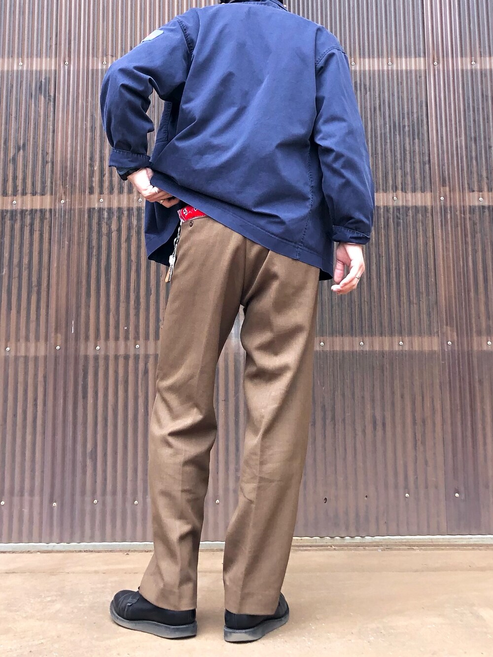 ブルー系のミリタリージャケット、ブルー系のシャツ/ブラウス、ブラウン系のスラックスを着用したメンズの春コーディネートの2枚目の写真