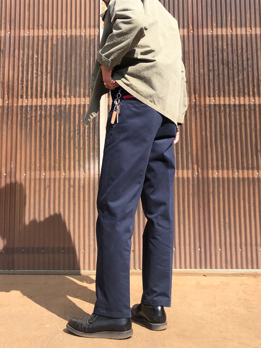 ブルー系のスラックス、ブラック系のブーツ、グリーン系のミリタリージャケットを着用したメンズの春コーディネートの2枚目の写真