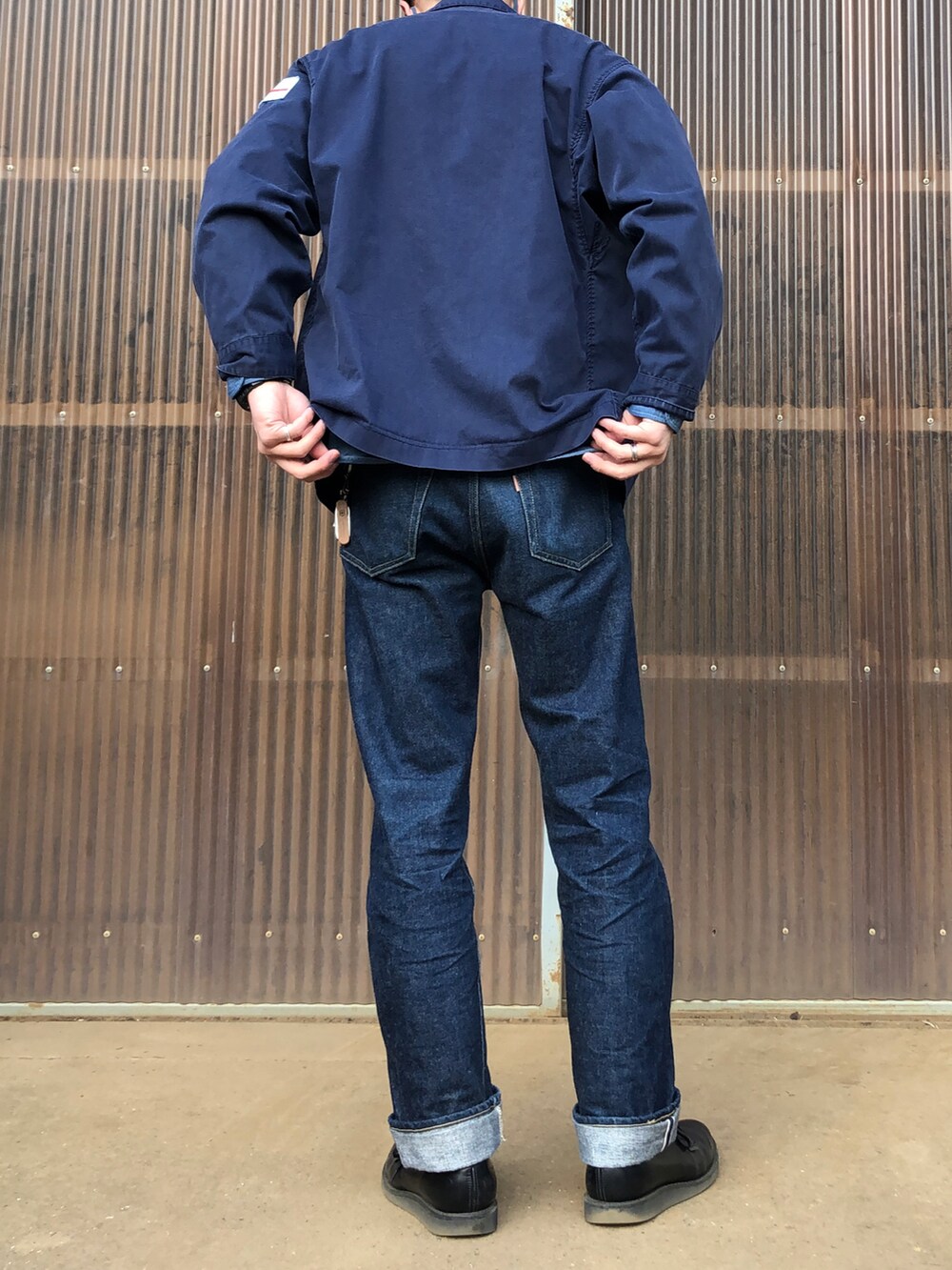 ブラック系のブーツ、ブルー系のデニムパンツ、ブルー系のミリタリージャケットを着用したメンズの春コーディネートの2枚目の写真