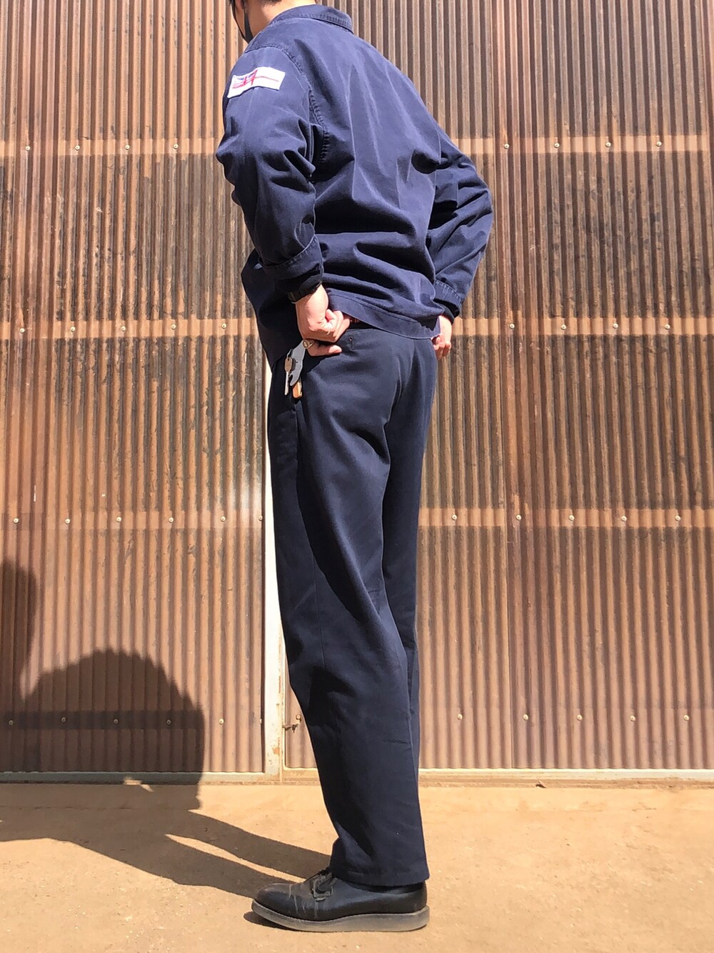 ブルー系のスラックス、ブラック系のブーツ、ブルー系のミリタリージャケットを着用したメンズの春コーディネートの2枚目の写真