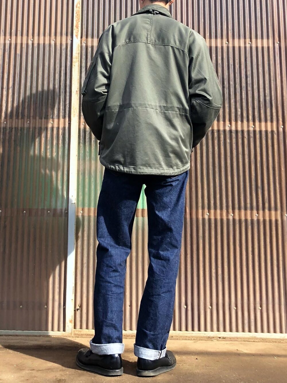 パープル系のスウェット、グリーン系のミリタリージャケット、ブルー系のデニムパンツを着用したメンズの冬コーディネートの2枚目の写真