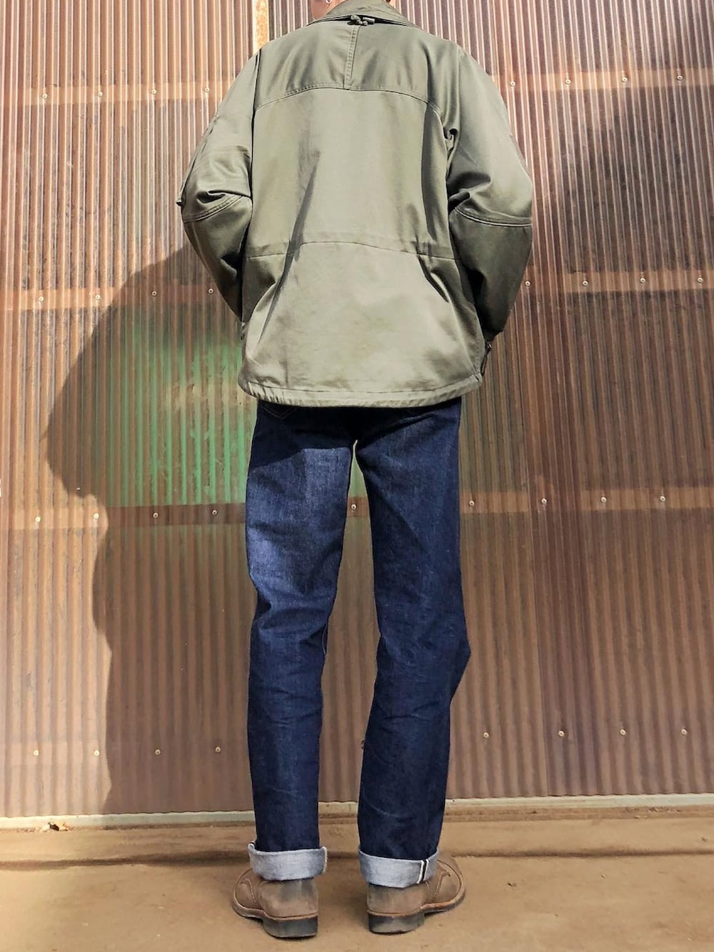 グリーン系のニット/セーター、グリーン系のミリタリージャケット、ブルー系のデニムパンツを着用したメンズの冬コーディネートの2枚目の写真