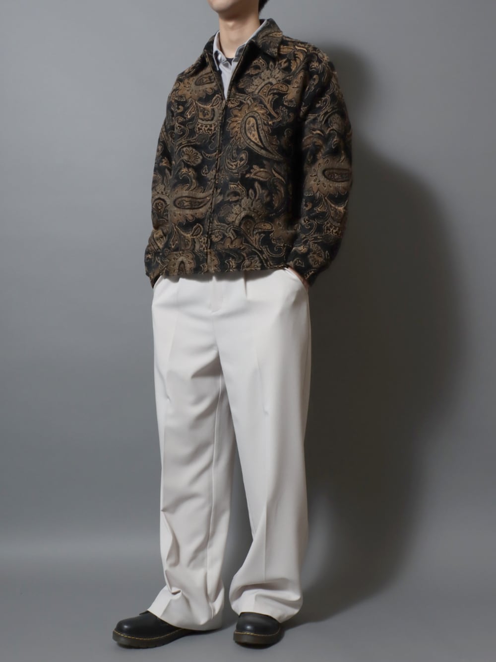 ブラック系のドレスシューズ、ホワイト系のスラックス、ブラック系のブルゾンを着用したメンズの春コーディネートの2枚目の写真