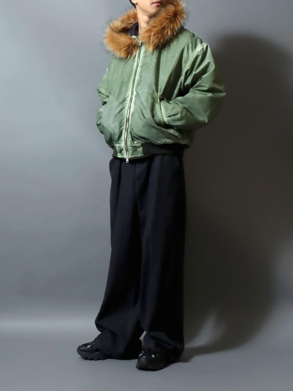 ブラック系のスラックス、グレー系のスウェット、グリーン系のブルゾンを着用したメンズの冬コーディネートの2枚目の写真