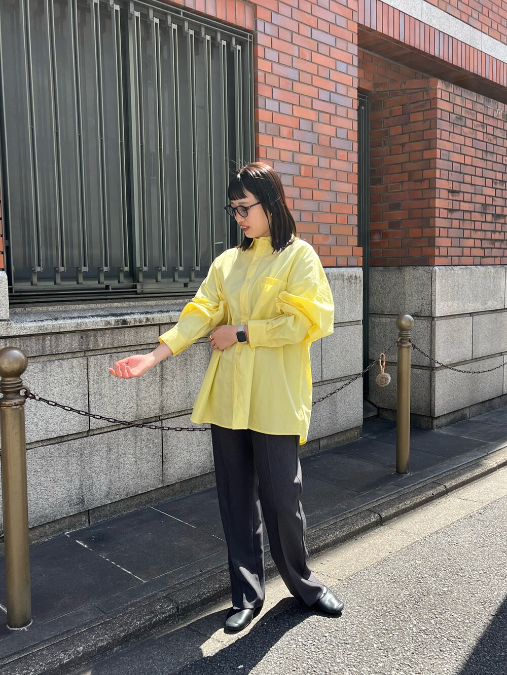 イエロー系のシャツ/ブラウス、グレー系のスラックスを着用したレディースの春コーディネートの2枚目の写真