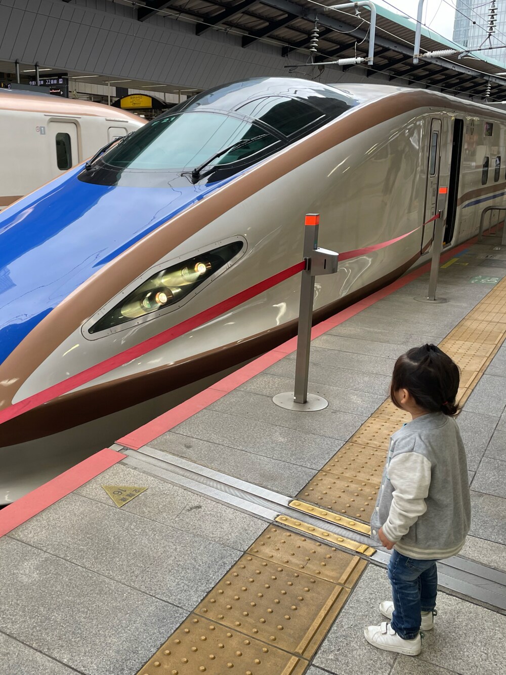 グレー系のスタジャン、ブルー系のデニムパンツ、ホワイト系のスニーカーを着用したキッズの夏コーディネートの3枚目の写真