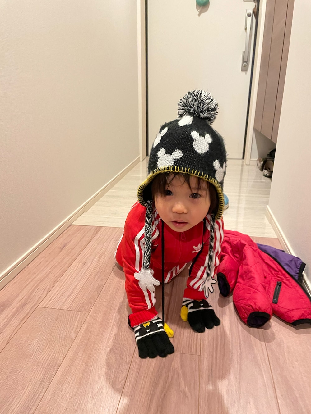 レッド系のその他アウター、ブラック系のニットキャップ/ビーニー、ブラック系の手袋を着用したキッズの冬コーディネートの2枚目の写真