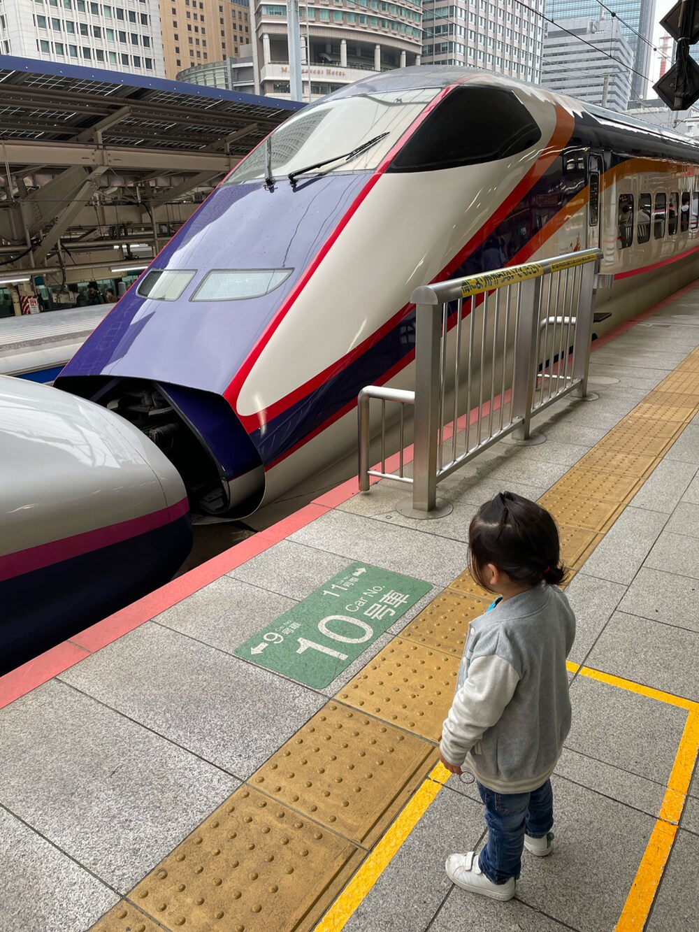 グレー系のスタジャン、ブルー系のデニムパンツ、ホワイト系のスニーカーを着用したキッズの夏コーディネートの2枚目の写真