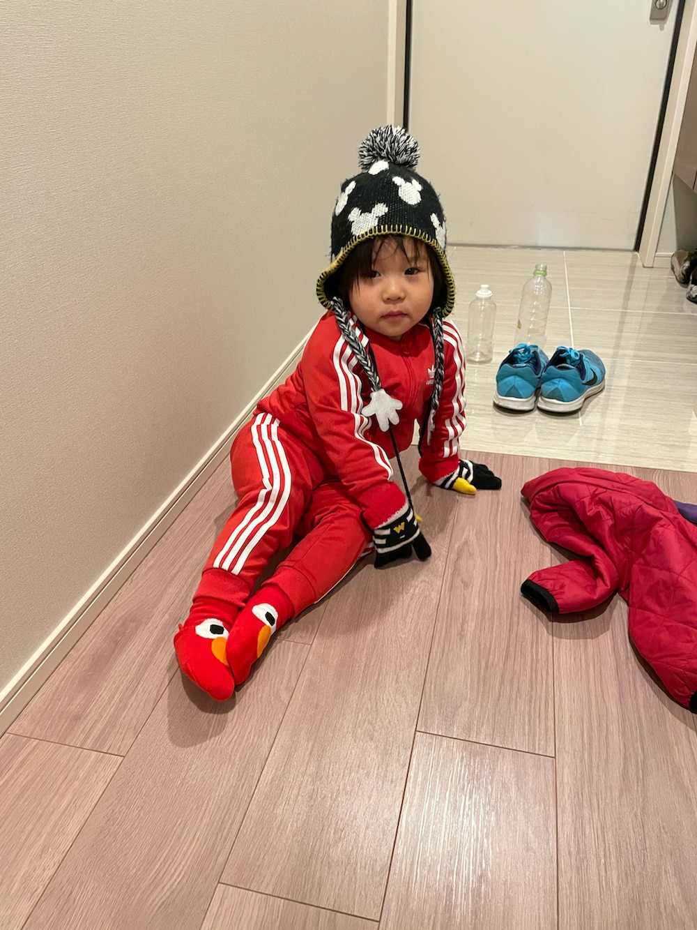 レッド系のその他アウター、ブラック系のニットキャップ/ビーニー、ブラック系の手袋を着用したキッズの冬コーディネートの5枚目の写真