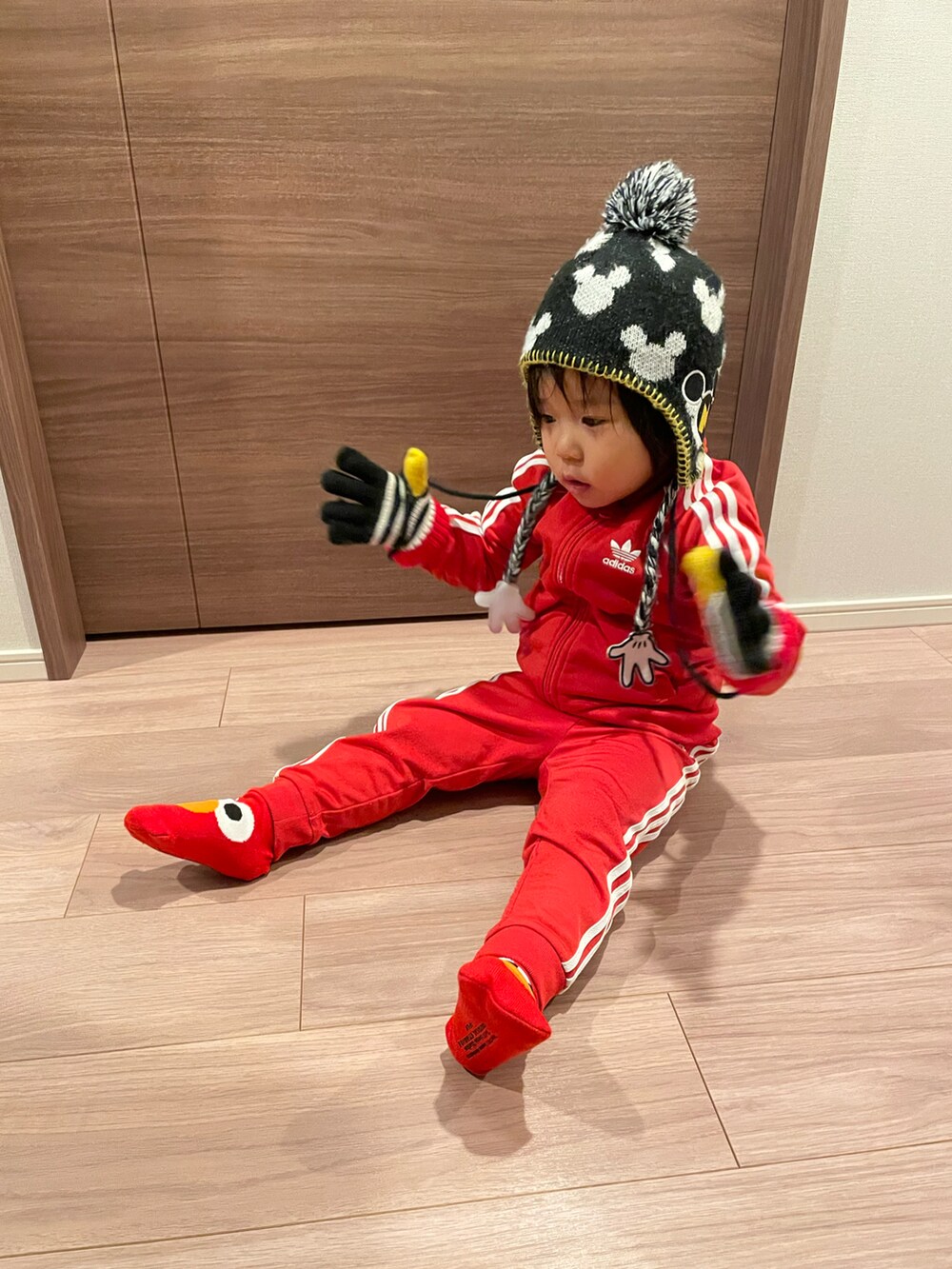 レッド系のその他アウター、ブラック系のニットキャップ/ビーニー、ブラック系の手袋を着用したキッズの冬コーディネートの3枚目の写真