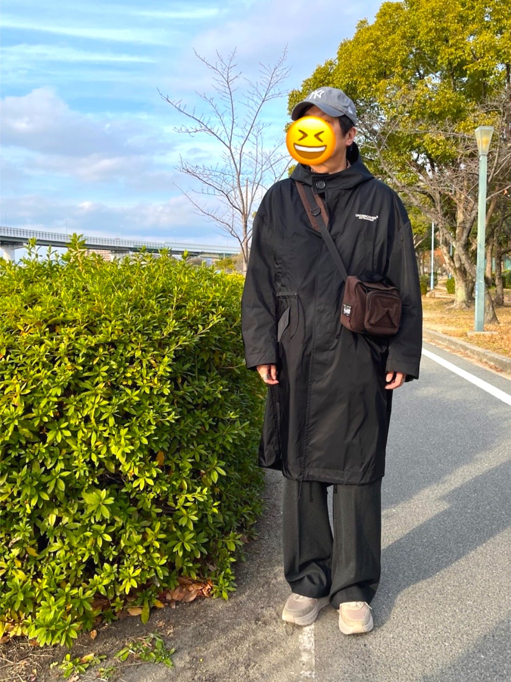 ベージュ系のスニーカー、ブラック系のモッズコート、ブラウン系のショルダーバッグを着用したメンズの冬コーディネートの2枚目の写真