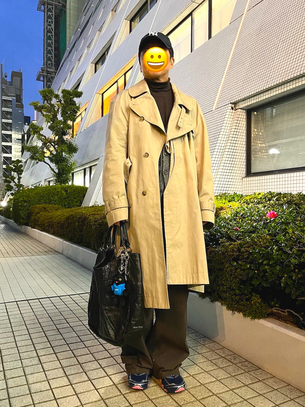 ベージュ系のトレンチコート、グレー系のカーディガン/ボレロ、ブラック系のトートバッグを着用したメンズの春コーディネートの3枚目の写真