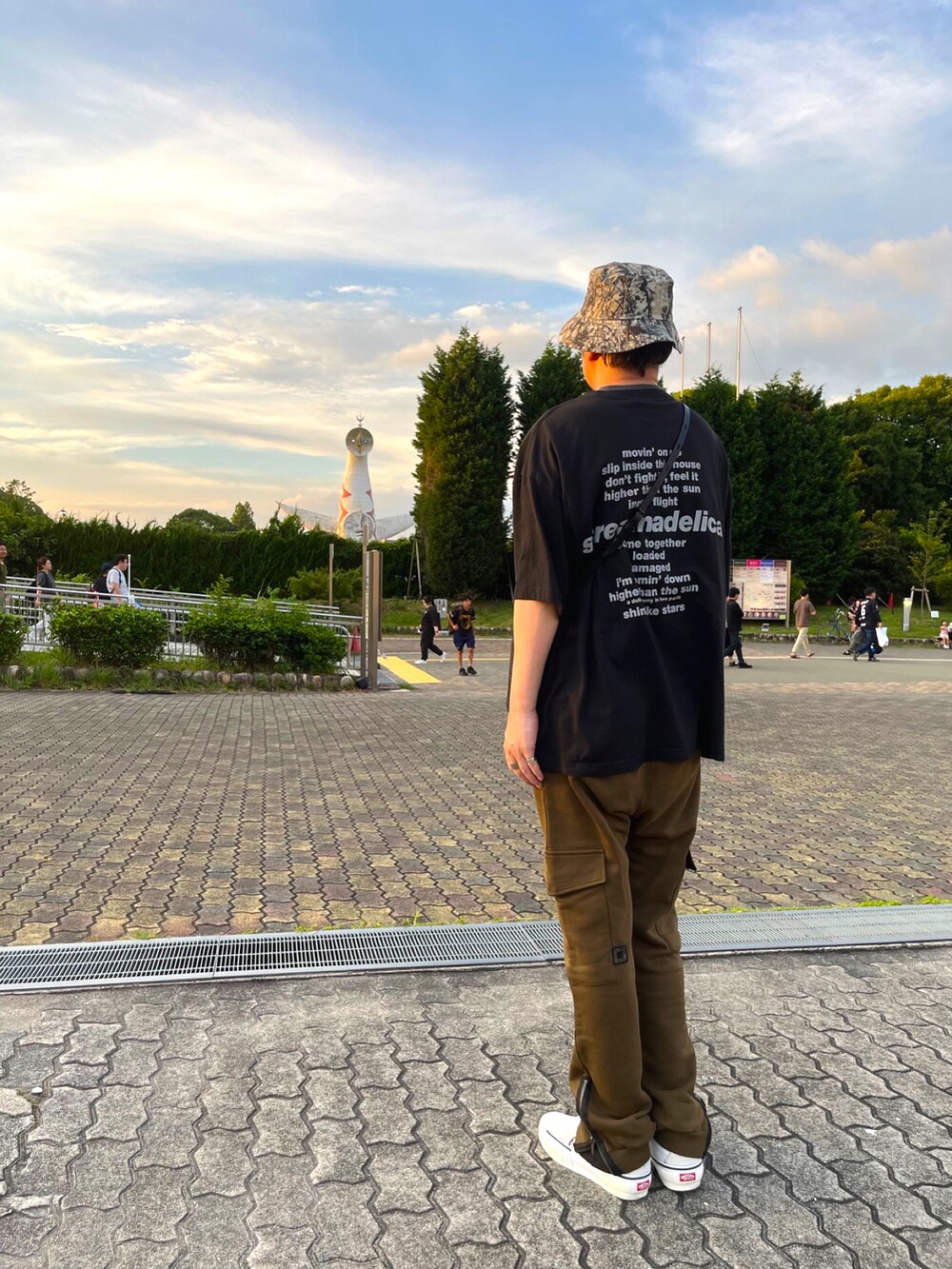 ホワイト系のスニーカー、ブラウン系のカーゴパンツ、ブラック系のTシャツ/カットソーを着用したメンズの夏コーディネートの2枚目の写真