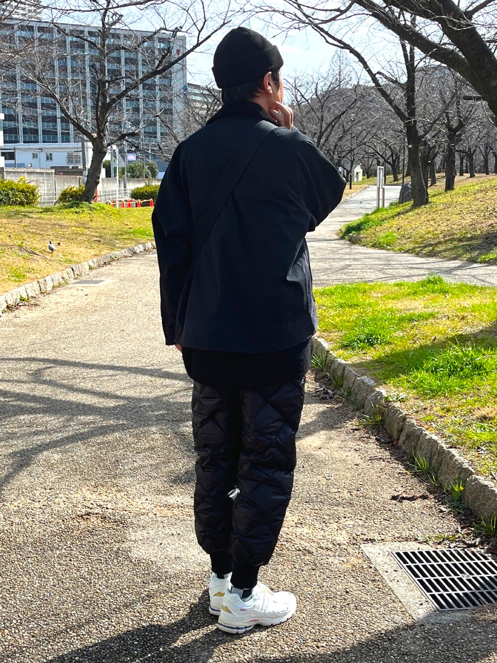 ホワイト系のスニーカー、ブラック系のその他パンツ、ブラック系のショルダーバッグを着用したメンズの冬コーディネートの4枚目の写真