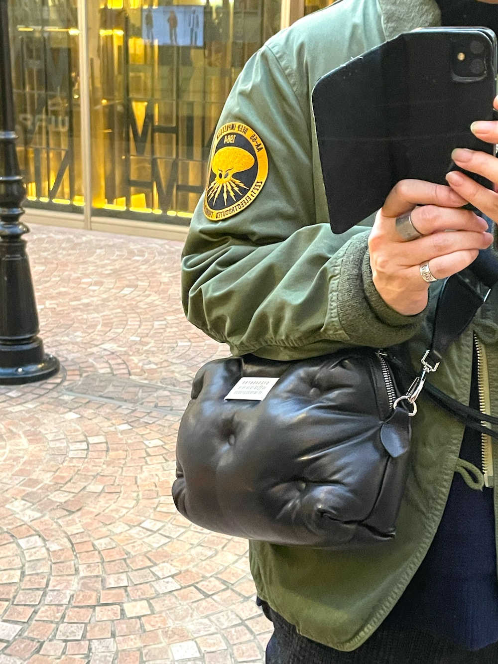 ブルー系のスニーカー、ブラック系のスラックス、ブラック系のショルダーバッグを着用したメンズの冬コーディネートの2枚目の写真