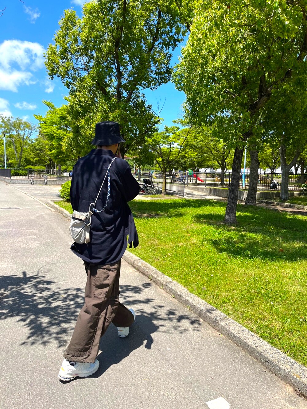 グリーン系のカーゴパンツ、ホワイト系のスニーカー、ブラック系のTシャツ/カットソーを着用したメンズの夏コーディネートの2枚目の写真