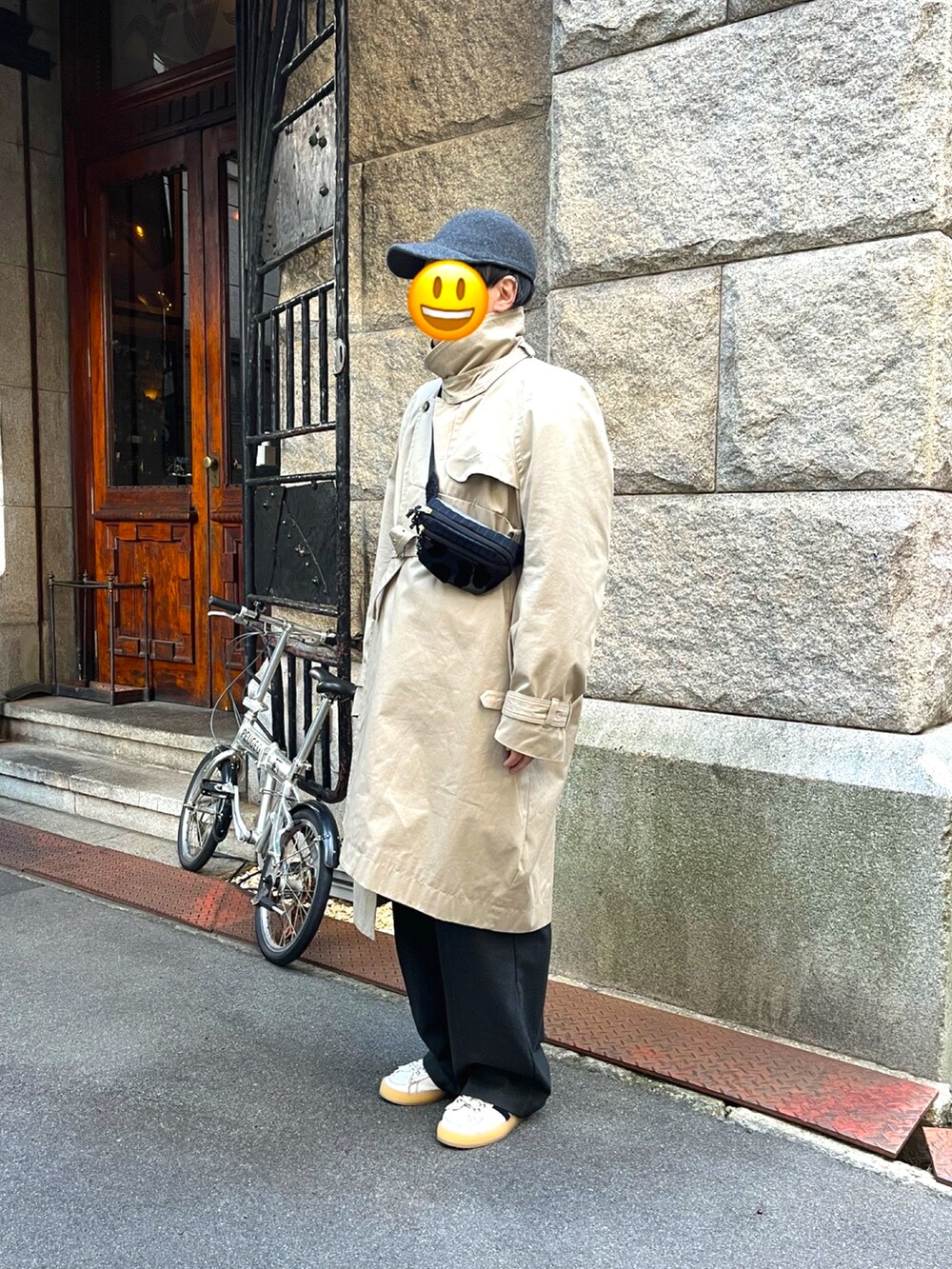 ホワイト系のスニーカー、グレー系のスラックス、ベージュ系のトレンチコートを着用したメンズの冬コーディネートの2枚目の写真